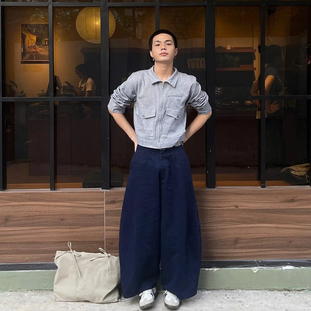 A person wearing a striped cropped jacket and wide-leg navy trousers standing outdoors.